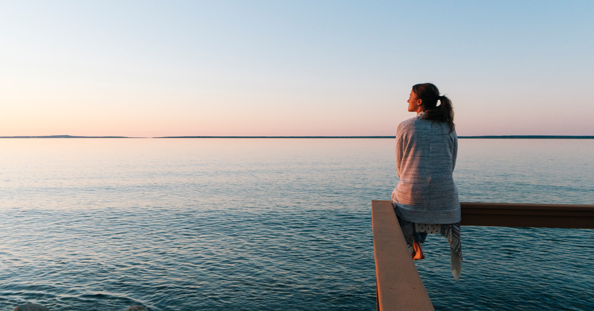 Woman sitting on dock by ocean.