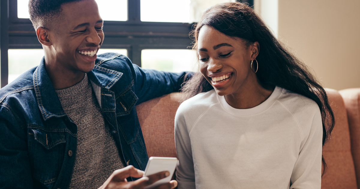 Young man and woman smiling at phone.