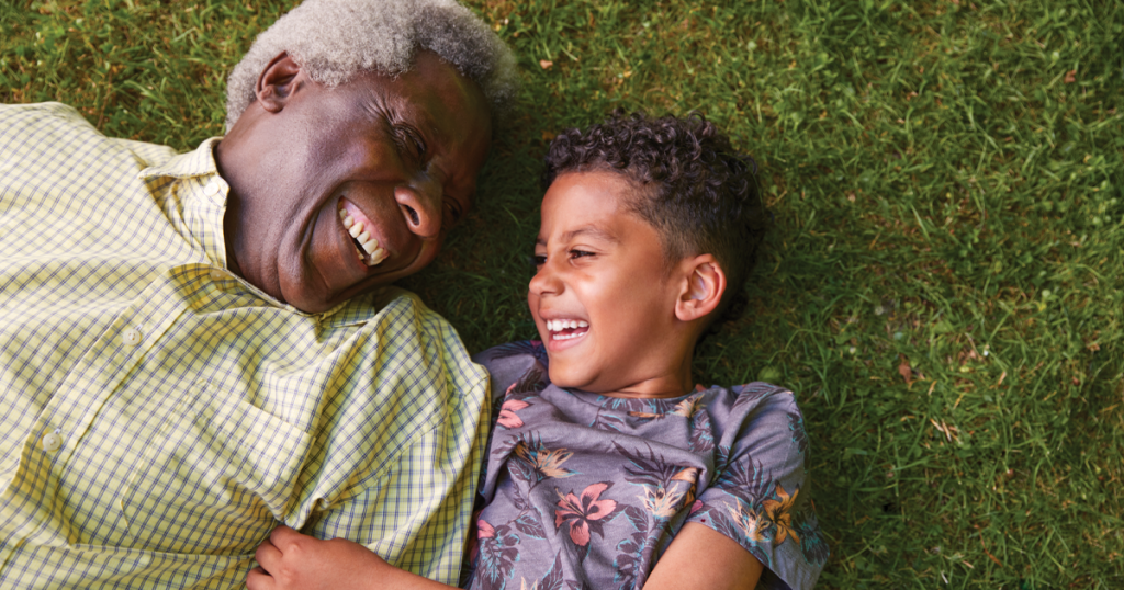 Boy and his granddad lying on grass, overhead close up